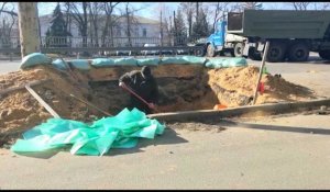 Un Ukrainien creuse une tranchée au milieu d'une route principale à Kiev