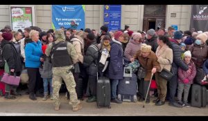 Ukrainiens et étrangers attendent un train à Lviv pour la Pologne