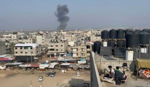 Des Gazaouis préparent du pain sur leur toit, de la fumée au loin