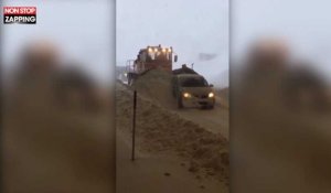 Un chasse-neige pousse une voiture bloquée par la neige (Vidéo)