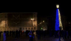 Des habitants de Kiev autour d'un sapin de Noël bleu et jaune le soir du Nouvel An