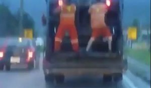 Deux eboueurs dansent sur leur camion poubelle