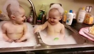 Ces jumelles s'amusent ensemble dans un évier