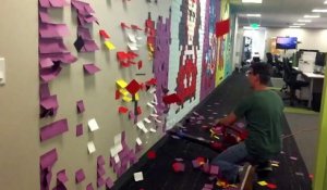 Des collègues de bureau enlève des fresque de Post-It au souffleur à feuilles