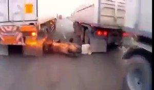 Un scooter chute entre des camions