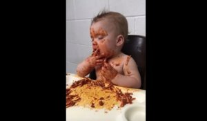 Un bébé fatigué mange des pâtes à la bolognaise