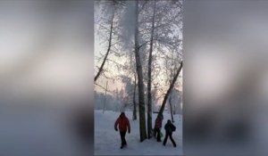 Le père tape dans cet arbre et la neige tombe sur ses enfants