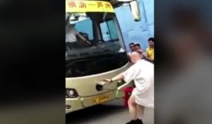 Le moine kung fu à moitié nu tire un bus de 18 tonnes le long d'une route avec son...
