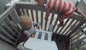 Un petit garçon aide son frère d'un an à s'échapper de son lit à barreaux