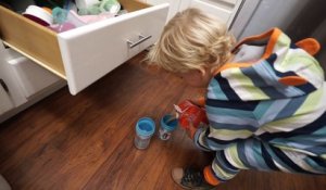 Un enfant de 3 ans prépare deux verres de jus de fruits