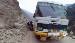 Ce motard croise une bus sur une route de montagne dans l'himalaya