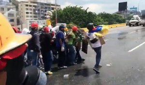 Des manifestants essayent du lutter contre le canon à eau de la police