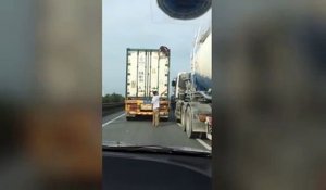 Une femme se cache sur le toit d'un camion qui roule sur une autoroute