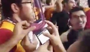 Un supporter du Galatasaray fait tomber son téléphone et le remonte à l'aide de plusieurs écharpes