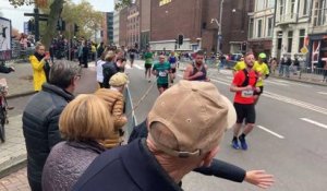 Une grand-mère encourage des coureurs en leur tapant avec un bâton