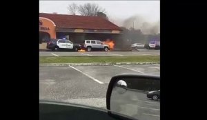 Un policier éloigne une voiture en feu d'un immeuble