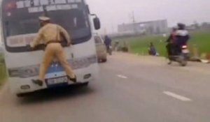 Un policier accroché à l'avant d'un bus au Vietnam