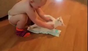 Ce bébé essaie de mettre une couche à son chat MDR !