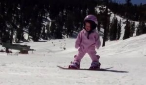 Une petite fille d'un an fait du snowboard