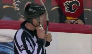 Un joueur de hockey coince sa crosse dans le casque de l'arbitre pendant un match