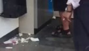 Un homme saoul retire de l'argent à un distributeur
