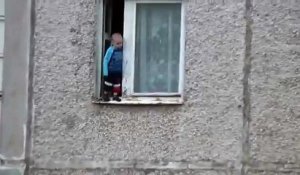 Un enfant joue sur le bord d'une fenêtre au 8ème étages