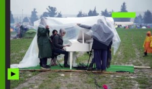 Une refugiée joue du piano sous la pluie dans check point grec