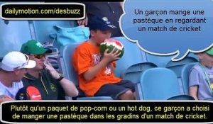 Un garçon mange une pastèque en regardant un match de cricket