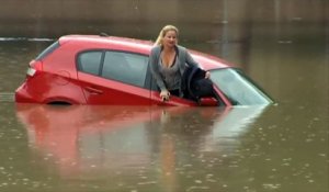 Une femme s'extirpe de son véhicule alors qu'il est en train de couler
