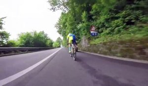 Un cycliste s’amuse à suivre une moto dans une descente de montagne