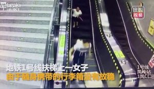Trop pressée dans l'escalator avec sa valise elle se vautre !