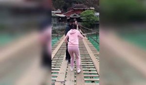 Terrifiée elle traverse un pont en bois suspendu au dessus d'une rivière