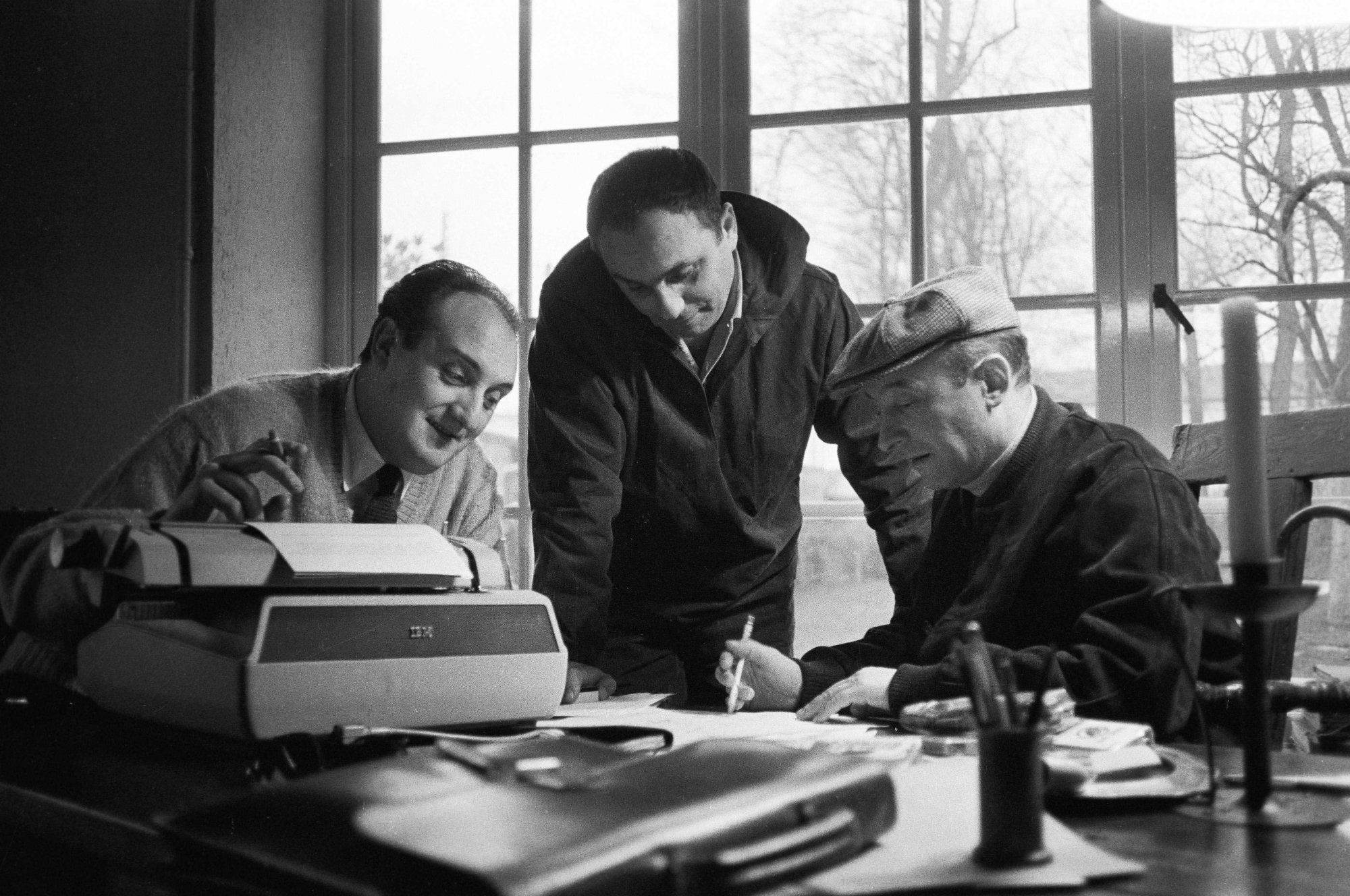 De gauche à droite : Pierre Tchernia, Marcel Bluwal et Michel Audiard travaillent chez Audiard à Paris, le 20 mars 1962.