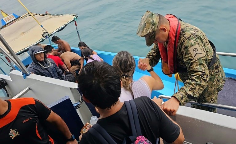Un soldat de la Marine équtorienne aide à monter à bord d'un bateau-taxi les rescapés d'un avion qui s'est abîmé en mer, sans faire de victimes, peu après son décollage de l'île de San Cristobal, sur l'archipel des Galapagos, le 12 février 2024