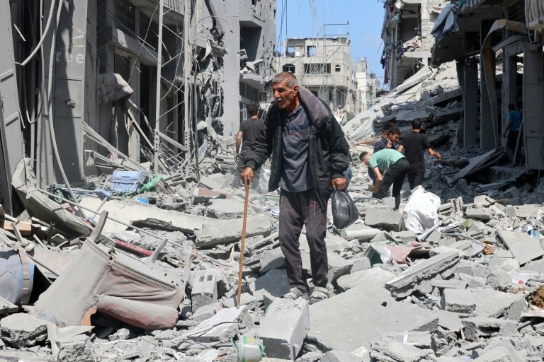 Des Palestiniens marchent le 14 mai 2024, au milieu de bâtiments détruits, dans une rue de Jabaliya, dans le nord de la bande de Gaza, où une guerre oppose Israël au mouvement islamiste palestinien Hamas