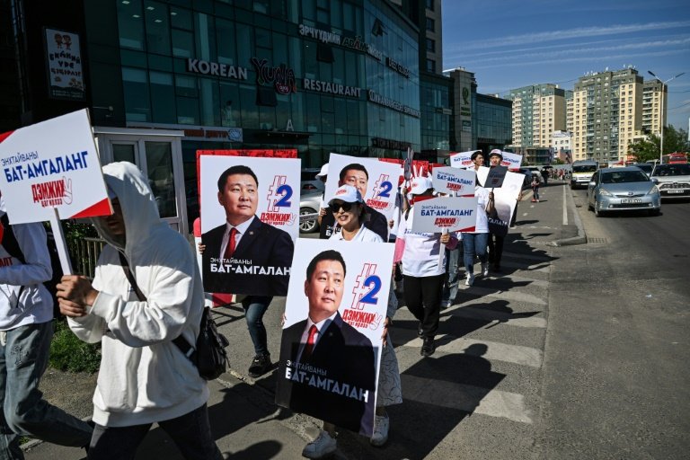 Un groupe de militants politiques marchent en tenant des affiches du candidat du Parti populaire mongol Bat-Amgalan Enkhtaivan, dans une rue d'Oulan-Bator en Mongolie, le 23 juin 2024, avant les élections législatives du 28 juin. 