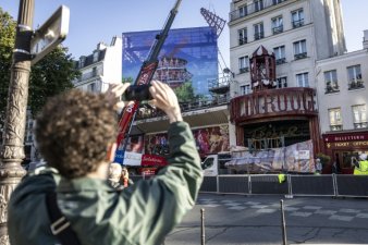 Des ouvriers installent l'une des quatre pales provisoires au sommet du cabaret le Moulin Rouge, après l'effondrement des anciennes ailes, le 24 juin 2024 à Paris