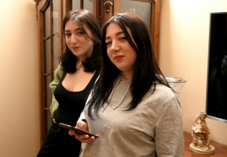 Les sœurs jumelles Anna Pantchoulidzé (g) et Elene Deisadzé regardent des photos lors d'une interview avec l'AFP à Tbilissi, le 23 mars 2024 en Géorgie