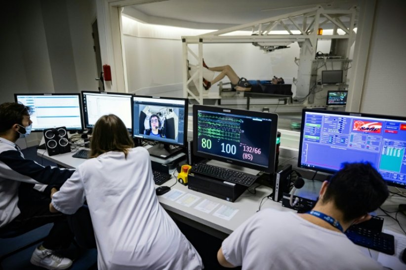 Du personnel médical étudie les données d'un volontaire allongé sur une centrifugeuse lors d'une expérience à la clinique de Medes, filiale santé du Centre national d'études spatiales (CNES), à Toulouse, le 23 mai 2023